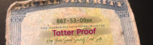 A worn Social Security card lying on a dark table.