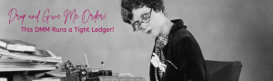 Old time black and white photo of a woman with reading glasses sitting hunched over at a cluttered desk looking directly at the camera with a no-nonsense look on her face.