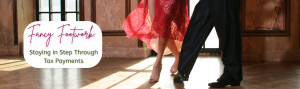 Man in black and woman in red from the feet down dancing in a sunlit ballroom.